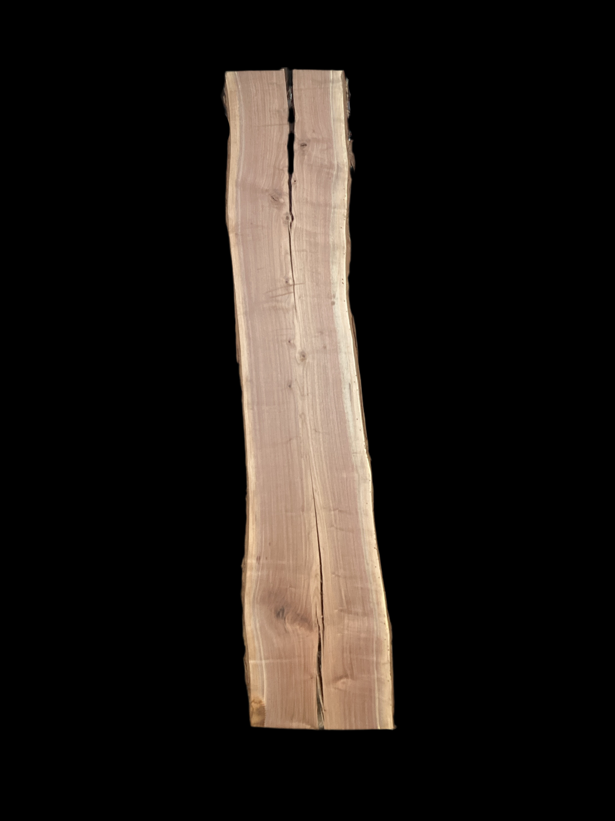 A long walnut wood slab with a split down the middle on a black background.