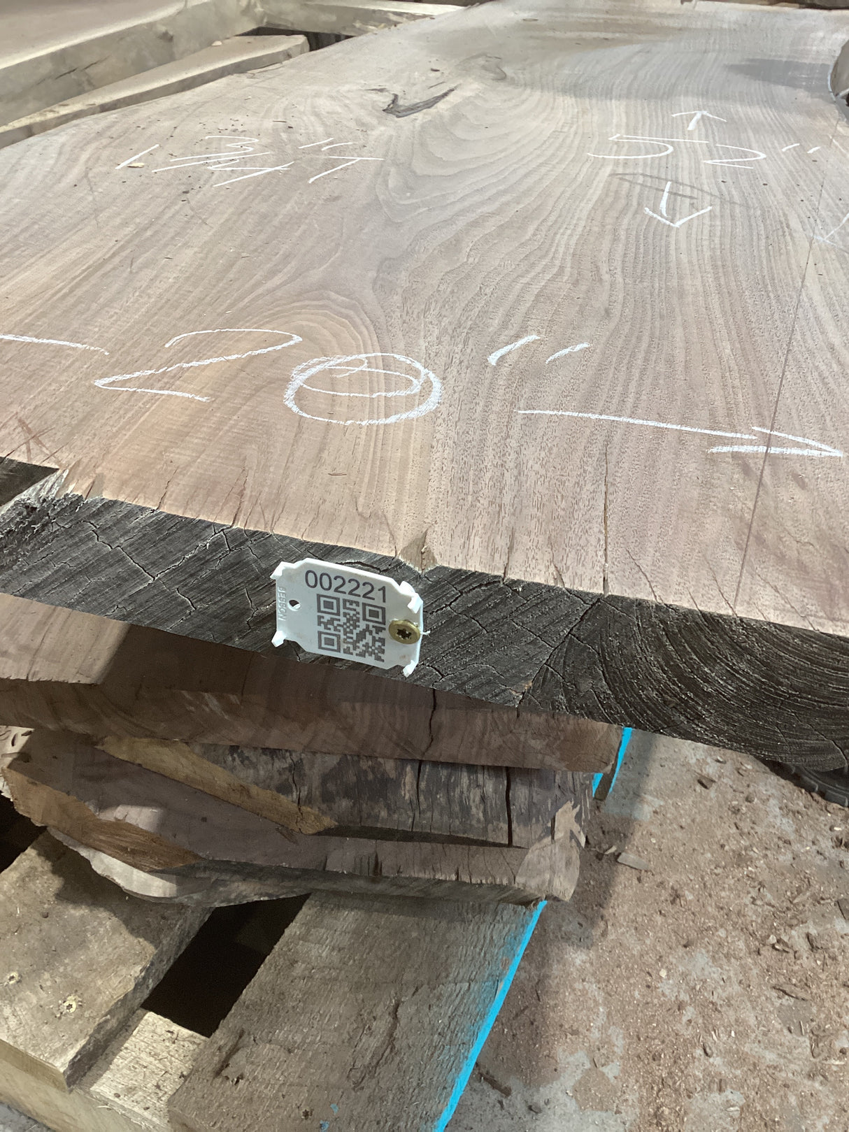 A walnut slab coffee table with visible wood grain and a QR label on top, placed on a wooden pallet.