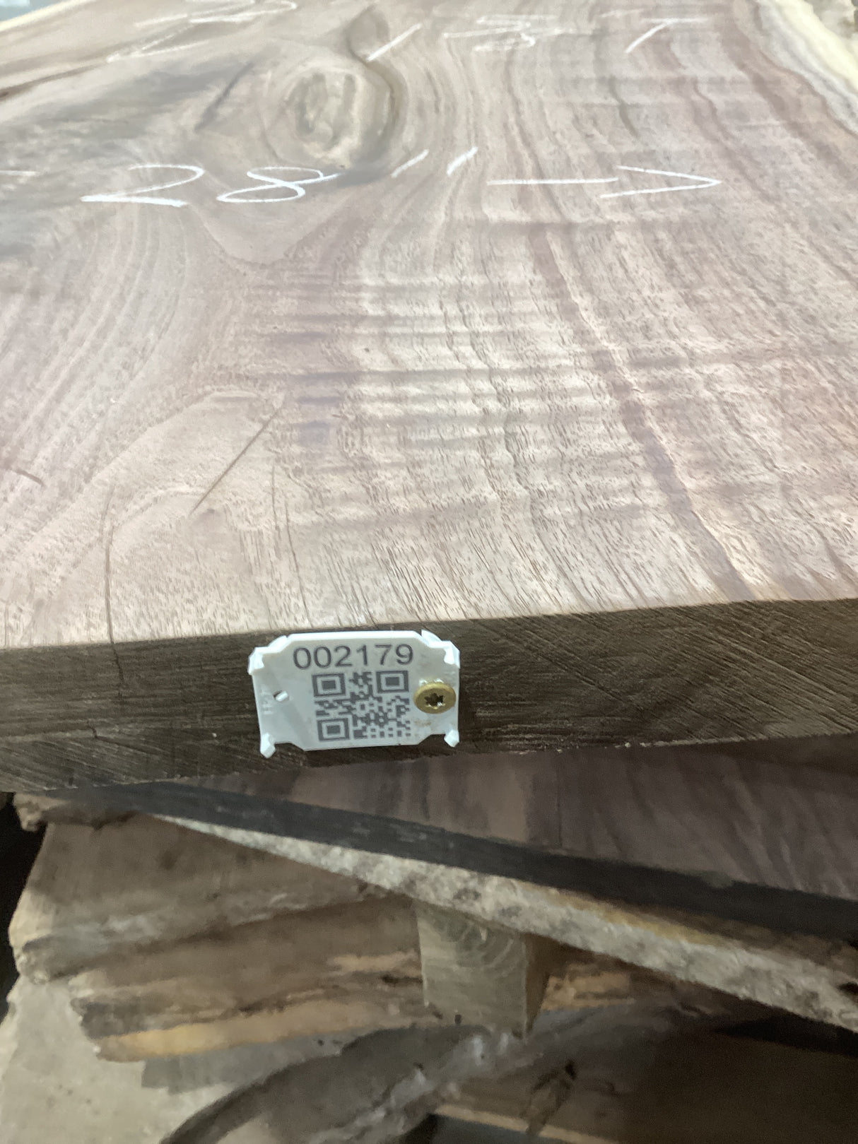 A walnut wood slab with a visible wood grain pattern and a QR tag attached to it.