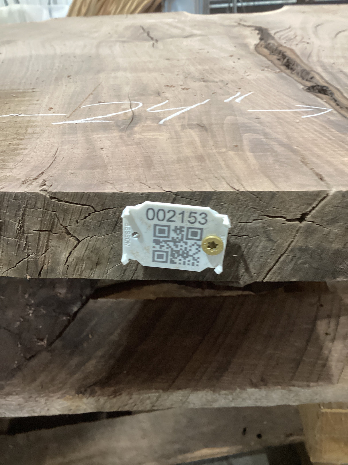 A walnut wood slab with a visible grain pattern, marked with a tag containing a QR code and number.