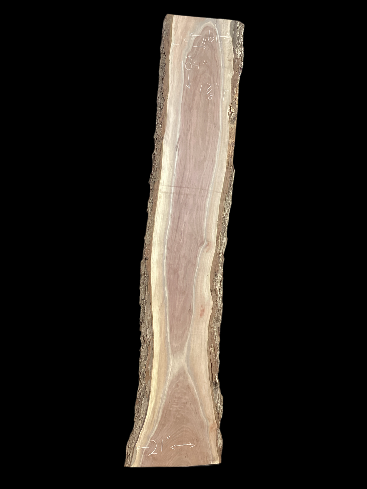 A long walnut wood slab on a black background.