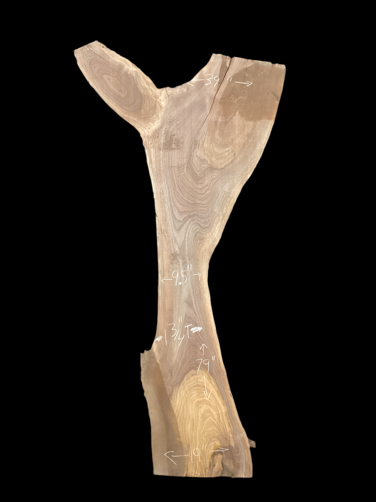 A irregular shaped walnut slab with a black background.