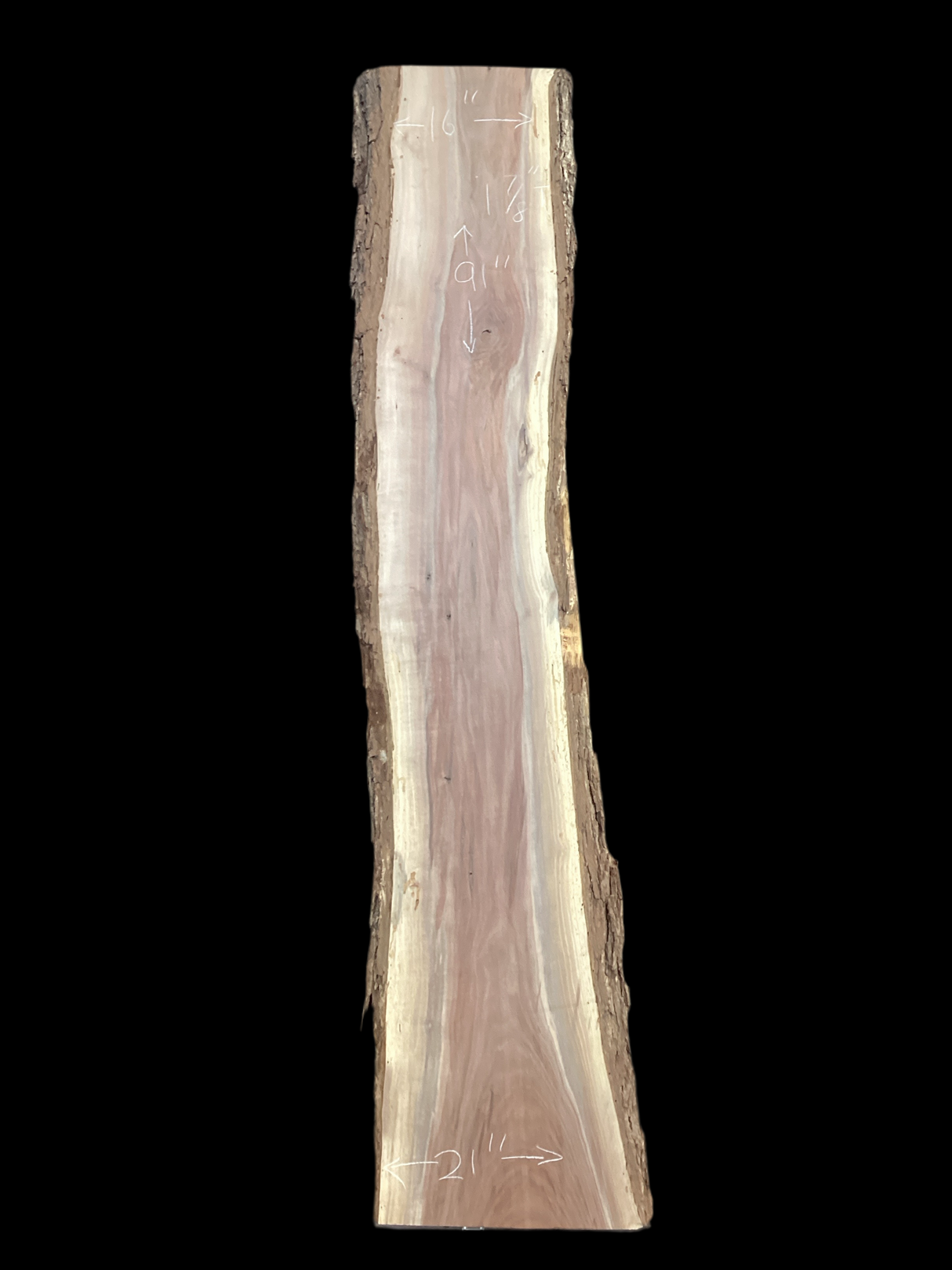 A long walnut wood slab on a black background.