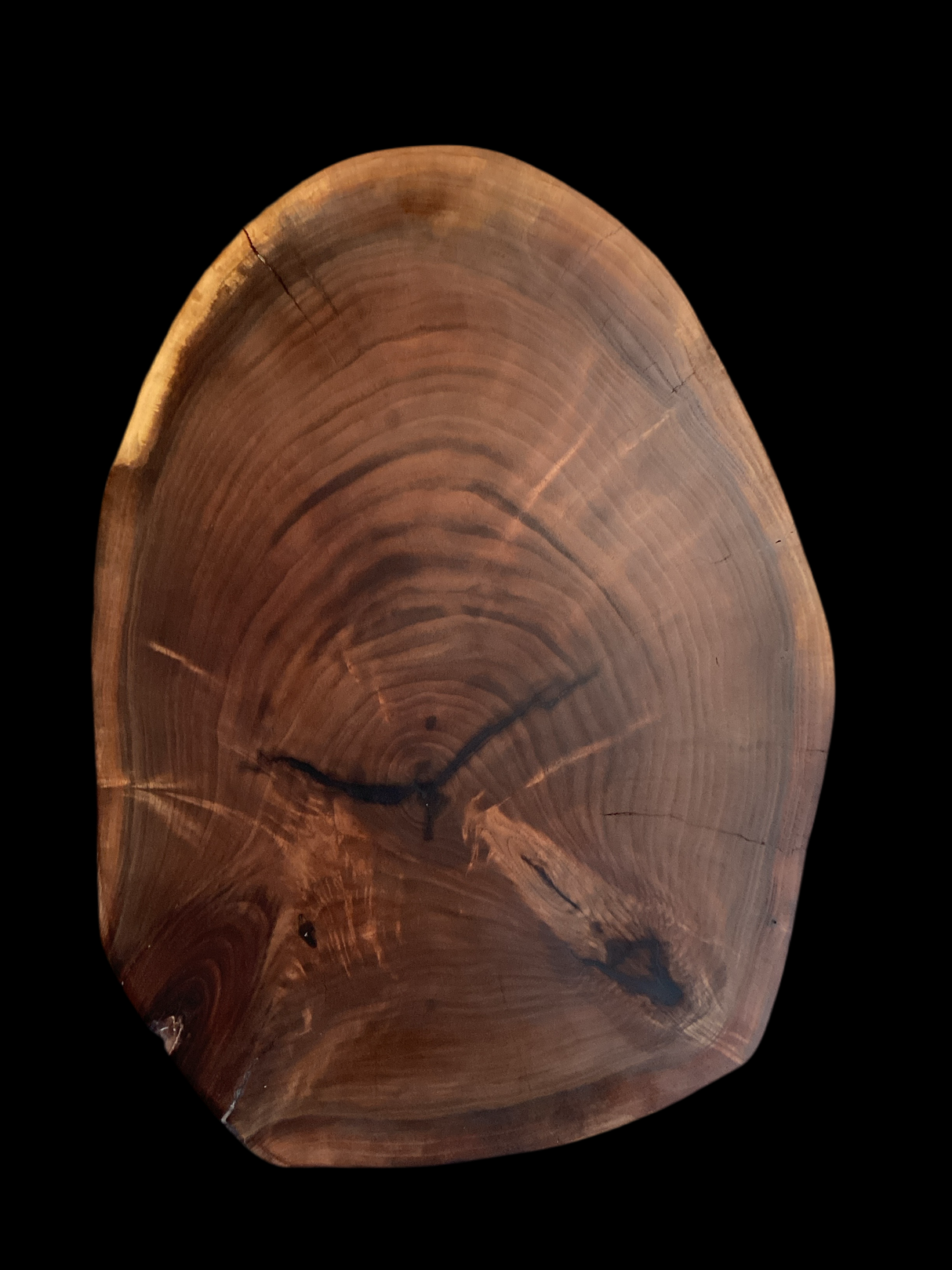 A one-of-a-kind black walnut charcuterie board with a curved edge and a rough, textured surface.