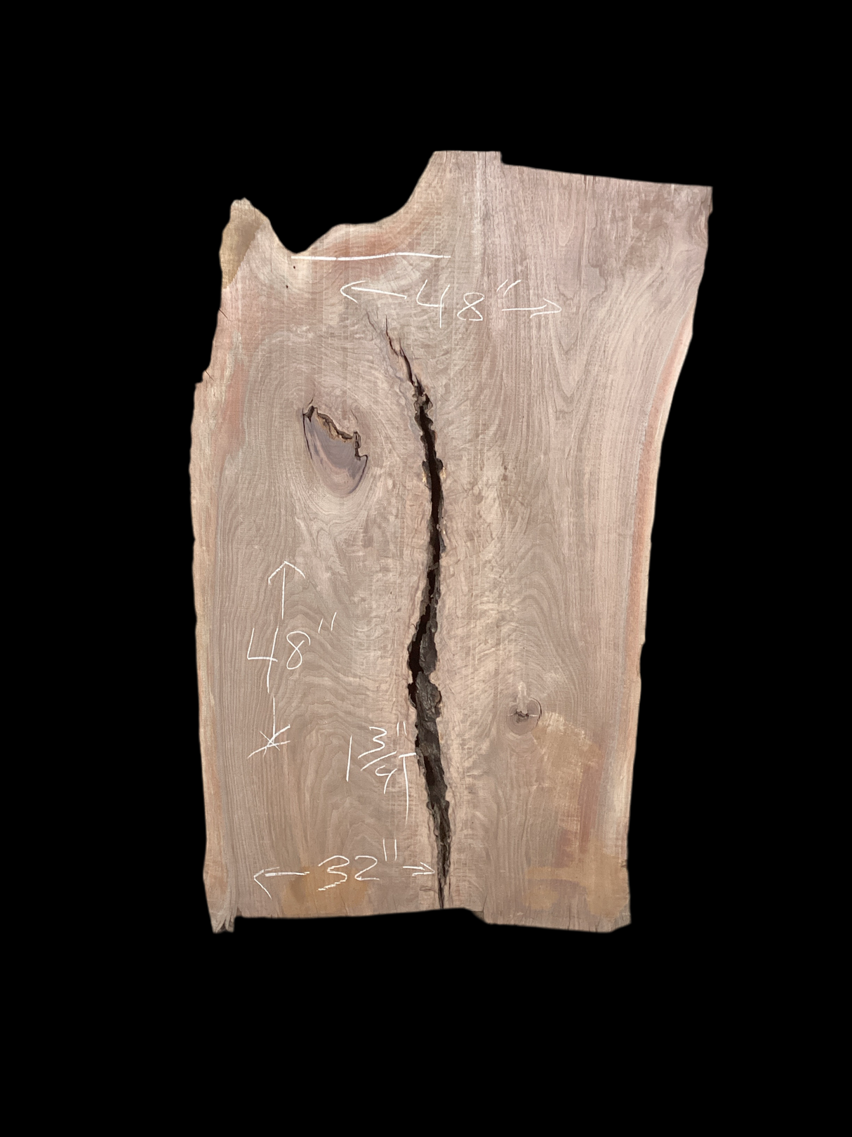 Irregular shaped walnut slab with a crack running through the middle and a black background.