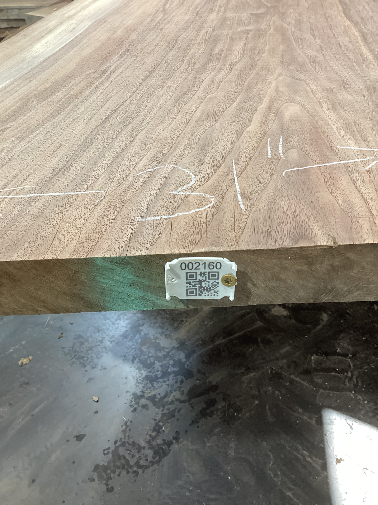 A walnut slab with visible wood grain patterns and a label with a barcode and measurements.