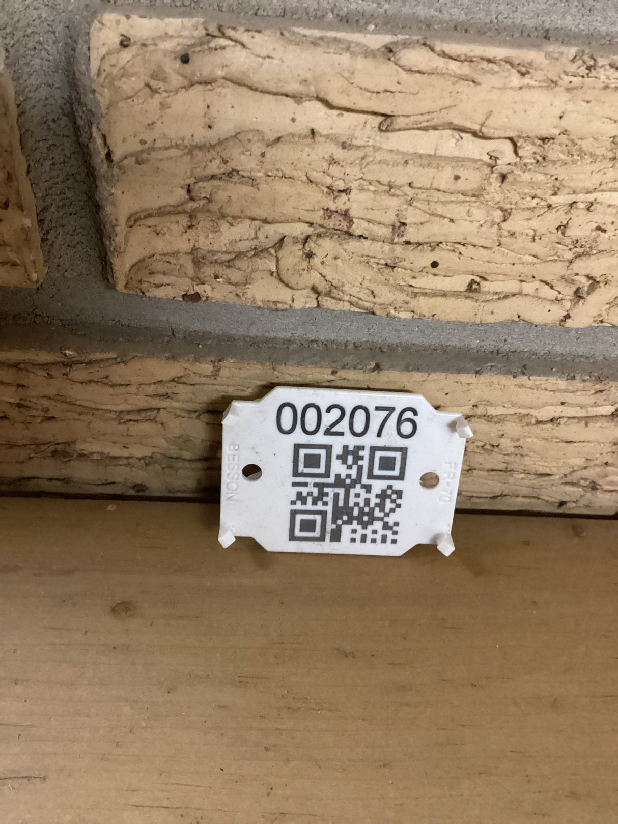 QR code with the sku 2076 positioned against a brick wall.