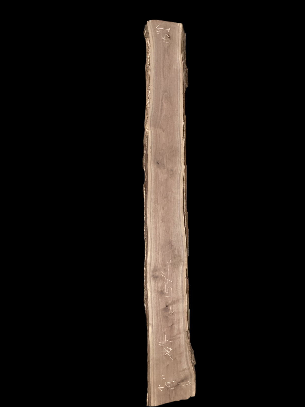 Large walnut wood slab propped on pallets with a black background.
