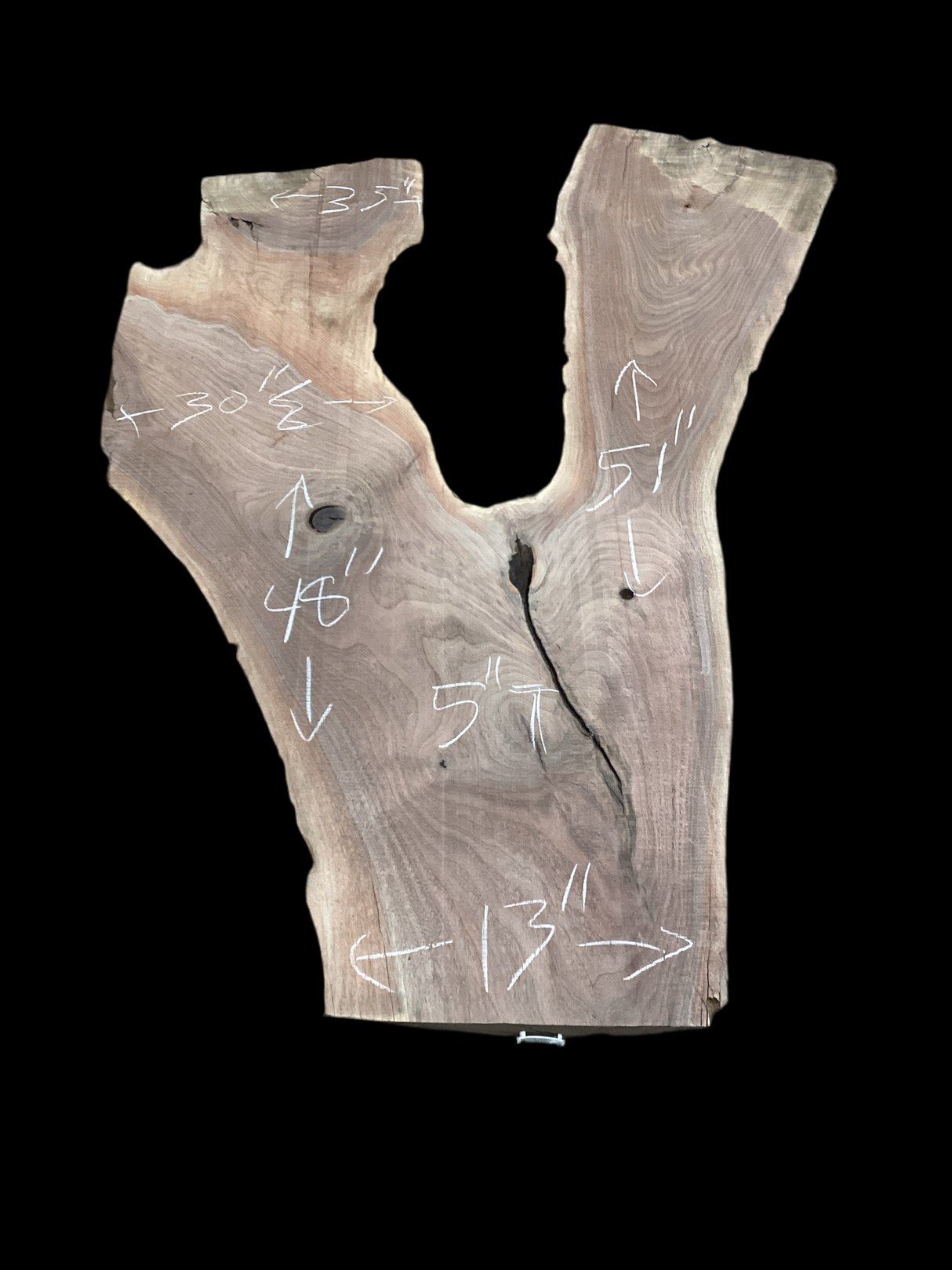 Irregular shaped walnut slab with a black background.