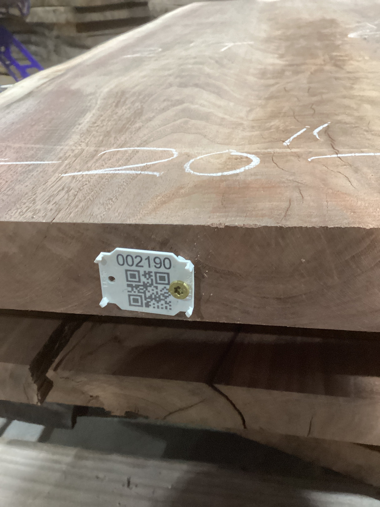 A walnut slab with a visible QR code and numerical code on the surface, indicating it may be part of a production or inventory system.