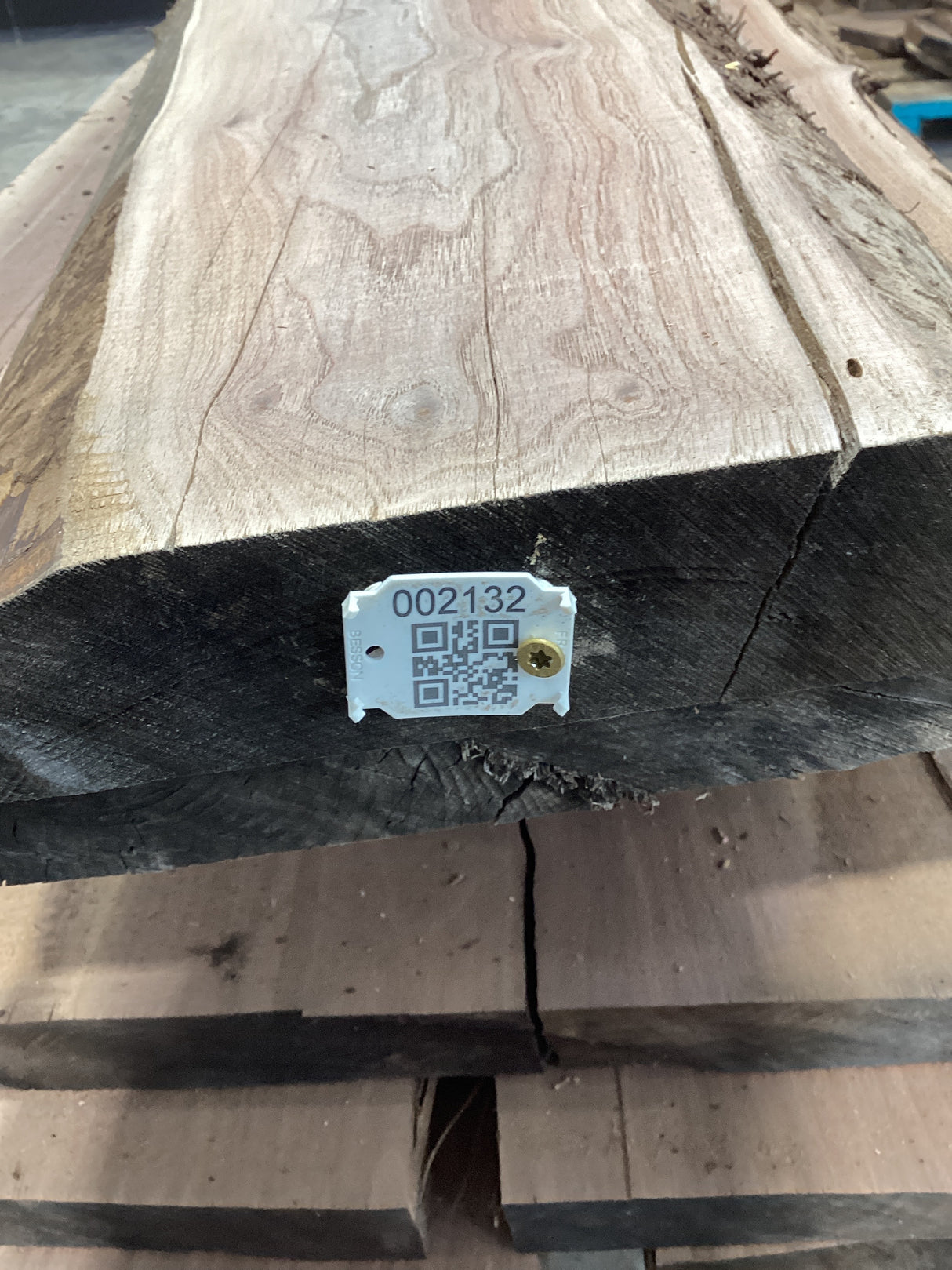 A walnut wood slab with a visible QR label stacked on wood.