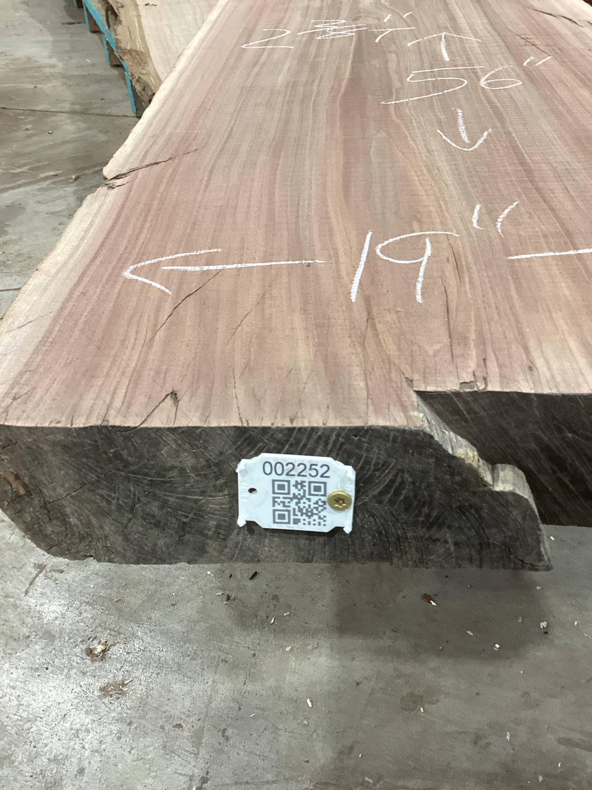 A walnut wood slab with natural edges and visible grain patterns, bearing a QR label with the sku.