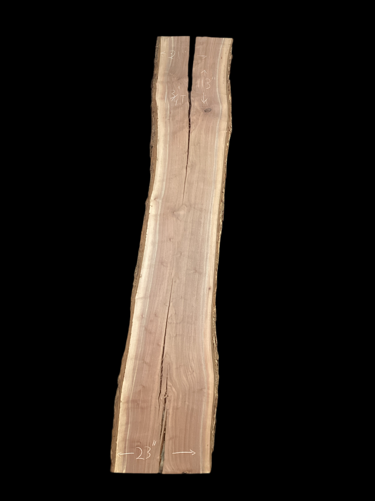 A long walnut wood slab with a split down the middle on a black background.