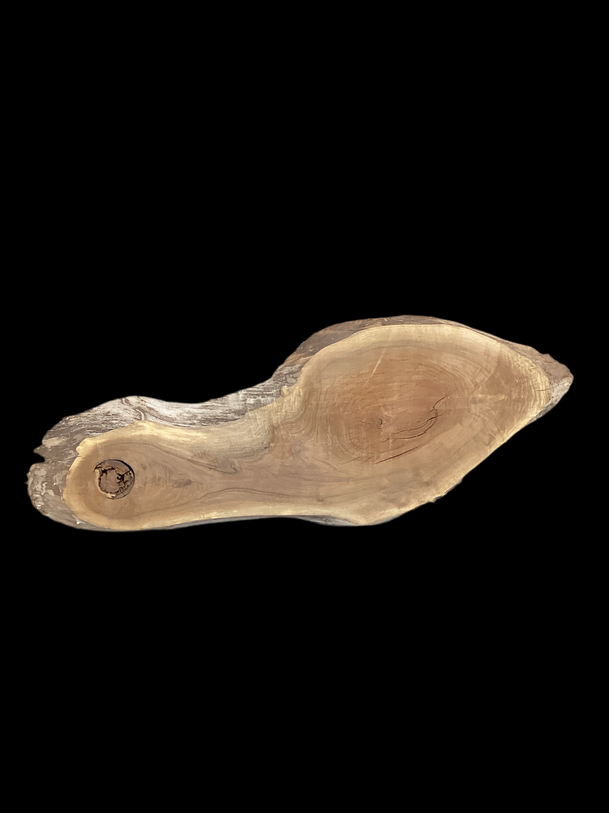 A walnut slab with a natural edge and a hole on one side, isolated on a black background.