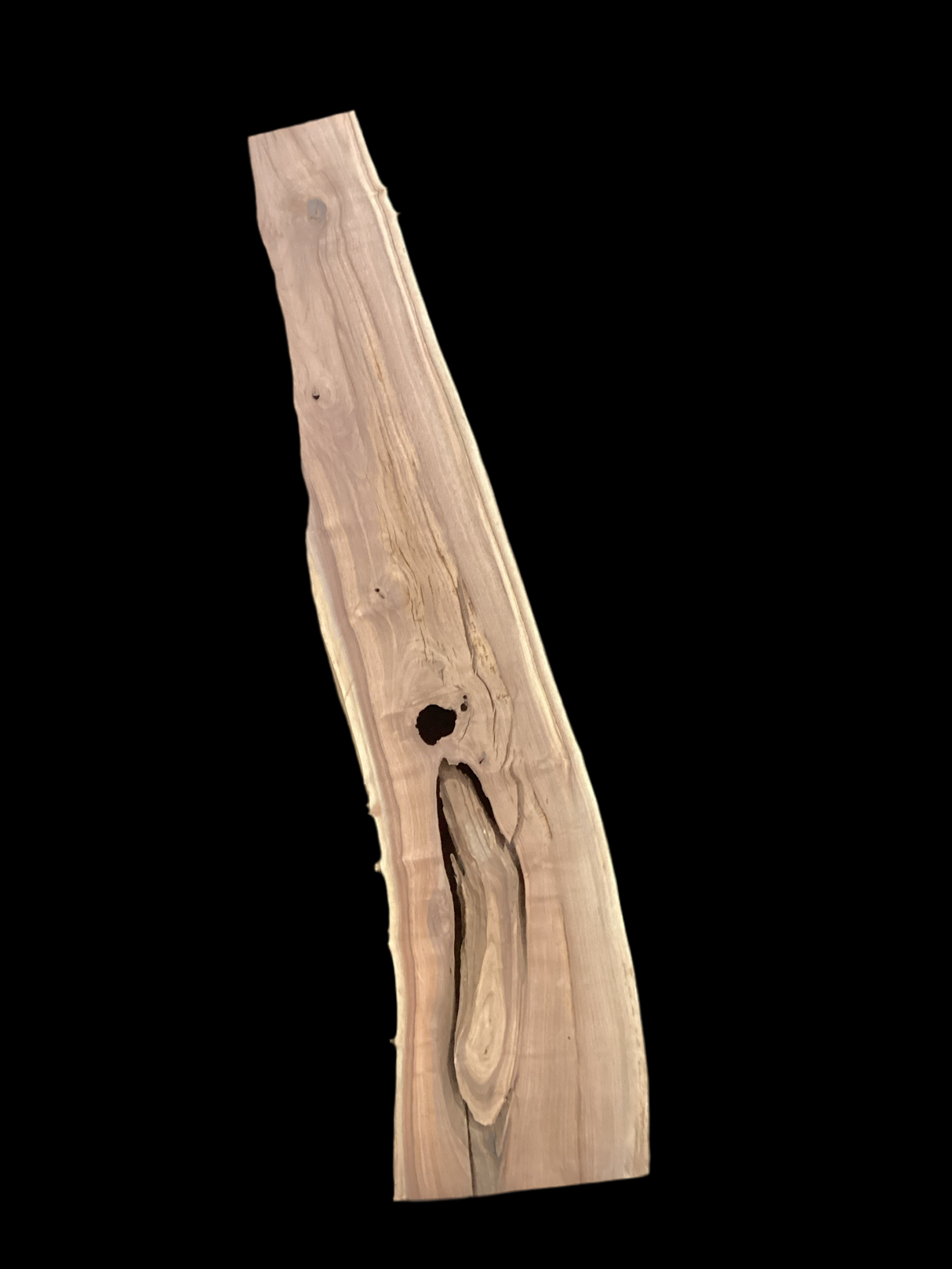 A long irregular shaped walnut slab with a black background.