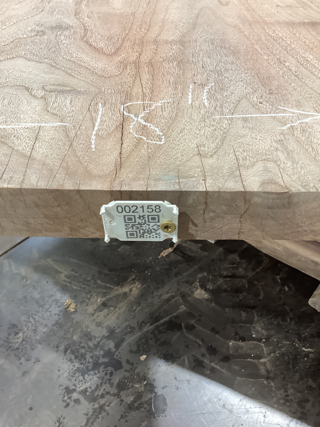 A walnut wood slab with visible natural grain patterns and a label with a QR code and measurements marked on it.