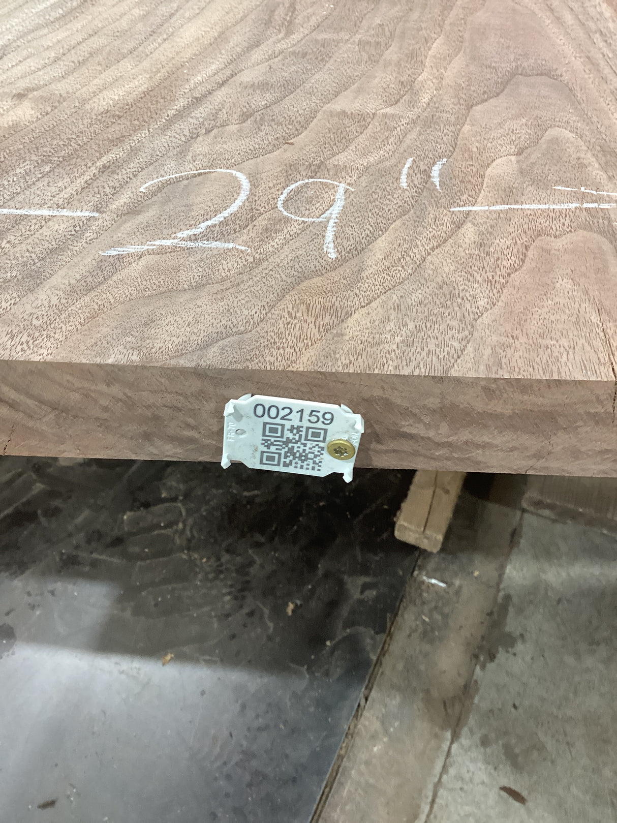A walnut slab with visible live edge marked with the measurement '29 inches' and a QR label indicating the product type and size.