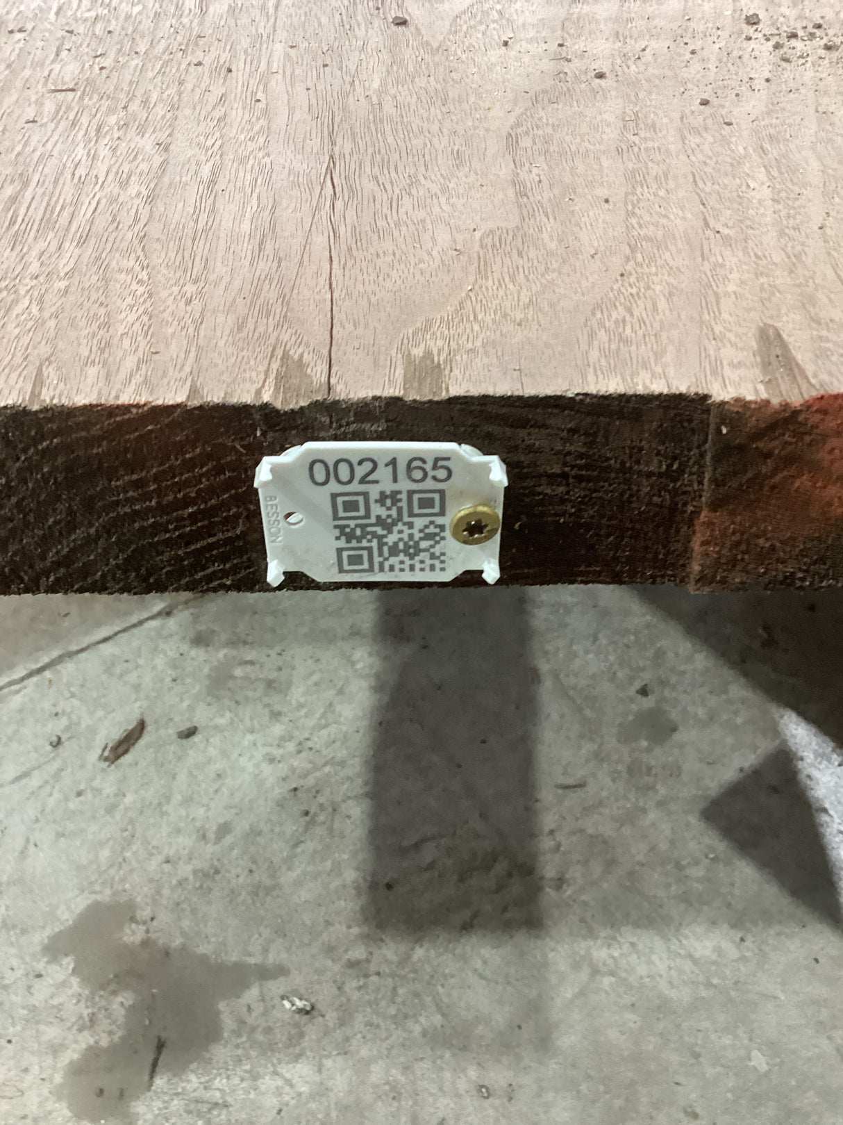 A walnut slab with a distinctive figure, marked with a QR code and an identification number, placed on a wooden surface.