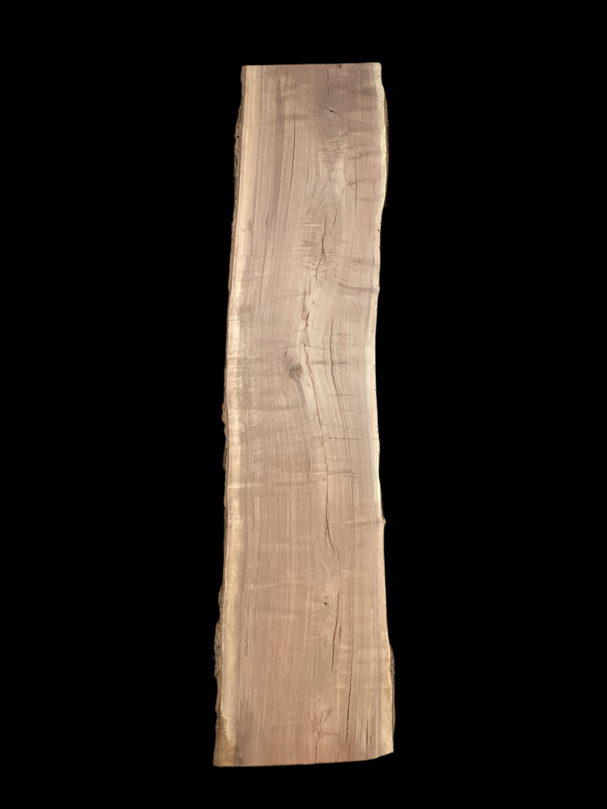 A long walnut wood slab on a black background.