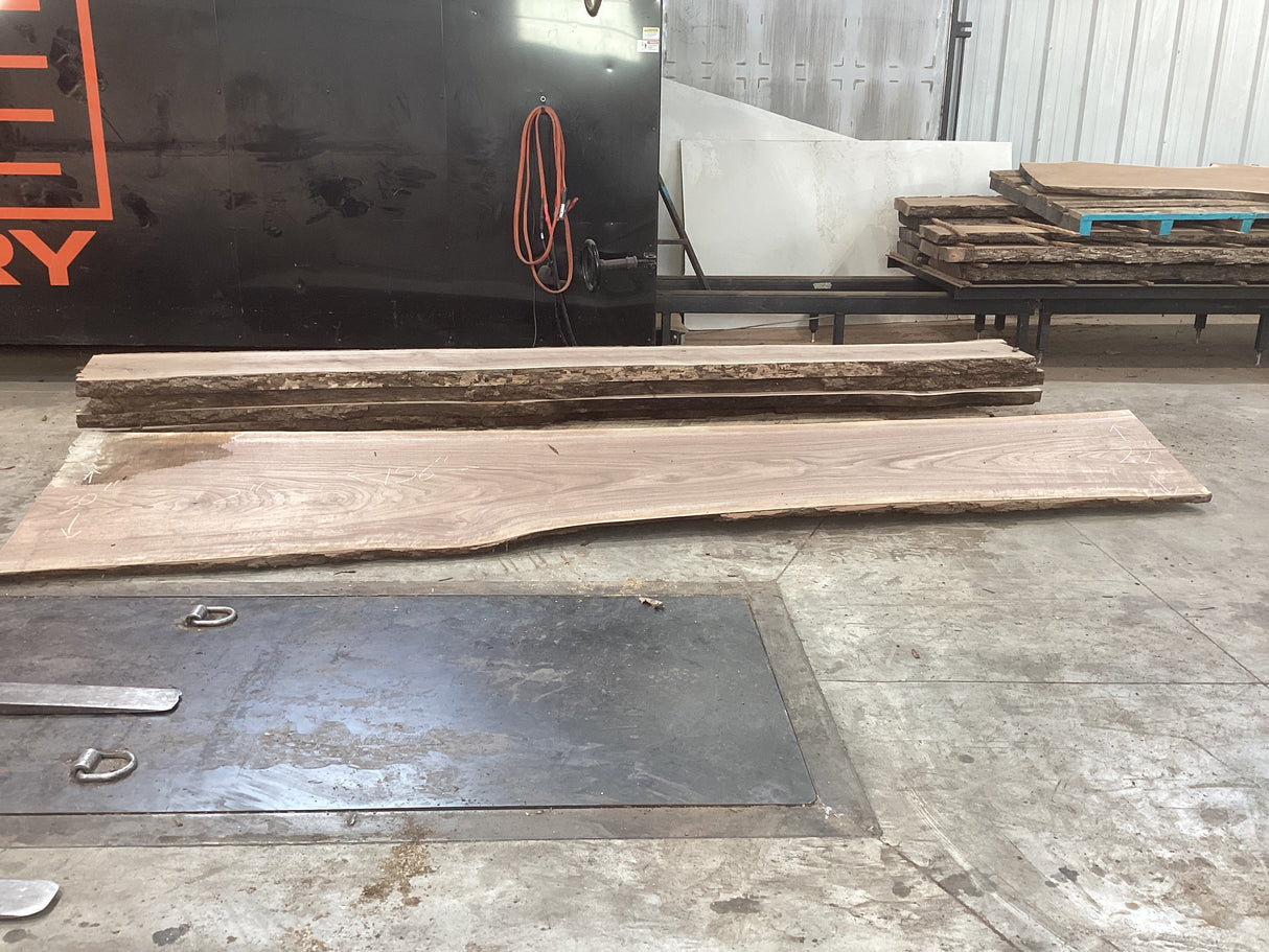 Pieces of large walnut slabs stacked up on top of each other on a concrete floor.