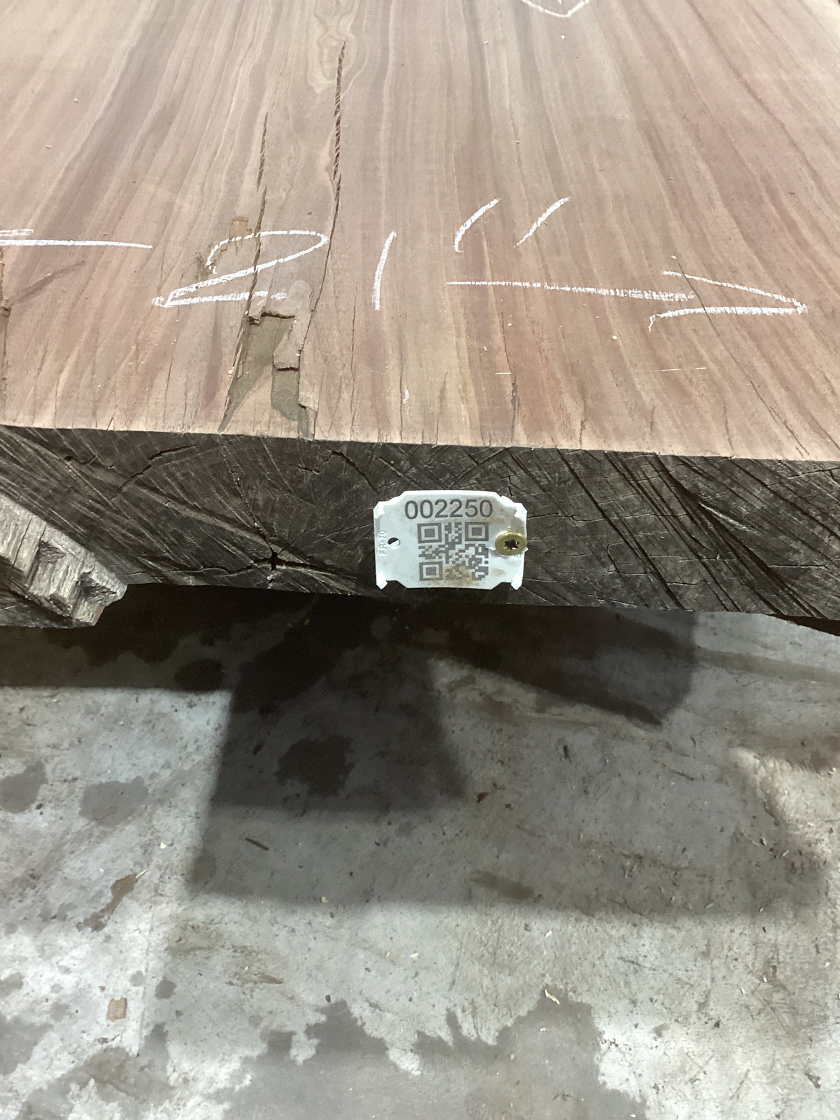 A walnut slab sofa table with visible wood grain and some defects, placed on a concrete surface with a QR label attached.