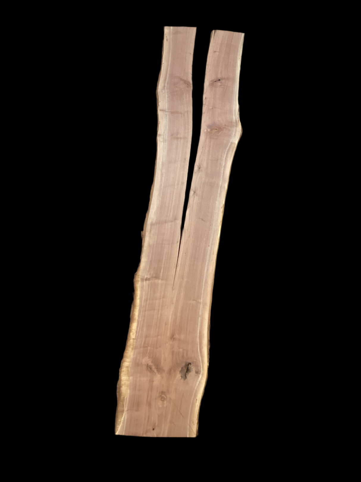 A long walnut wood slab with a split down the middle on a black background.