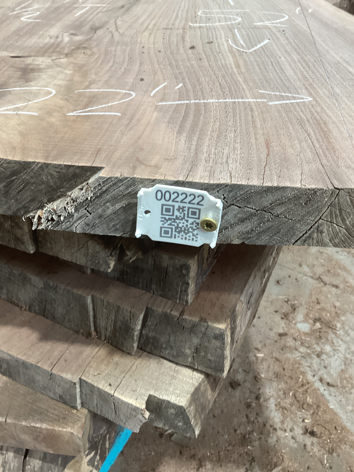 Stacked walnut wood slabs with a visible QR code on the uppermost slab.