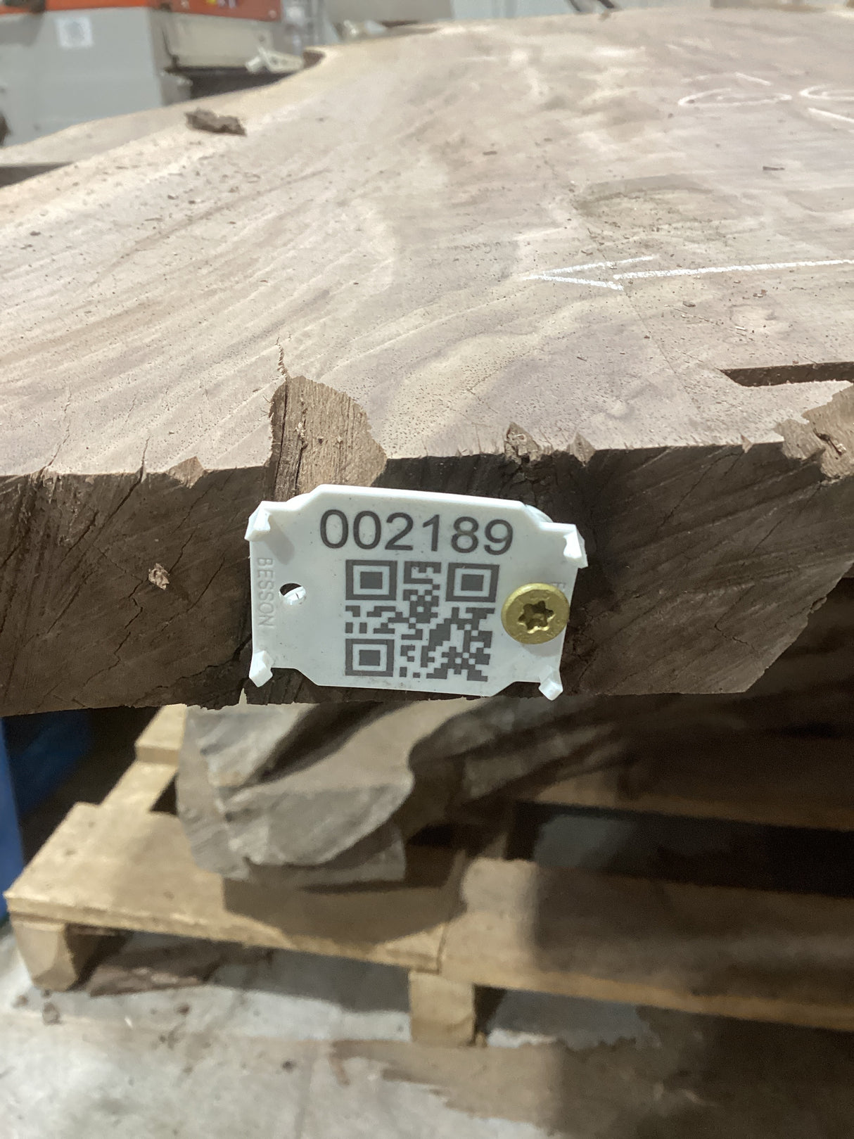 A medium sized walnut slab with visible checking, mounted on a wooden support structure, marked with a numeric code and a QR code.