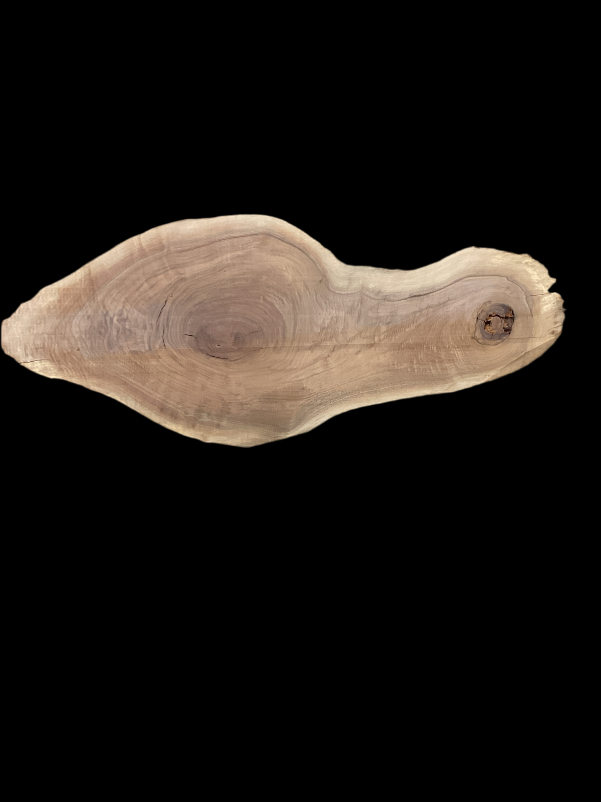 A walnut slab with a natural edge and a hole on one side, isolated on a black background.