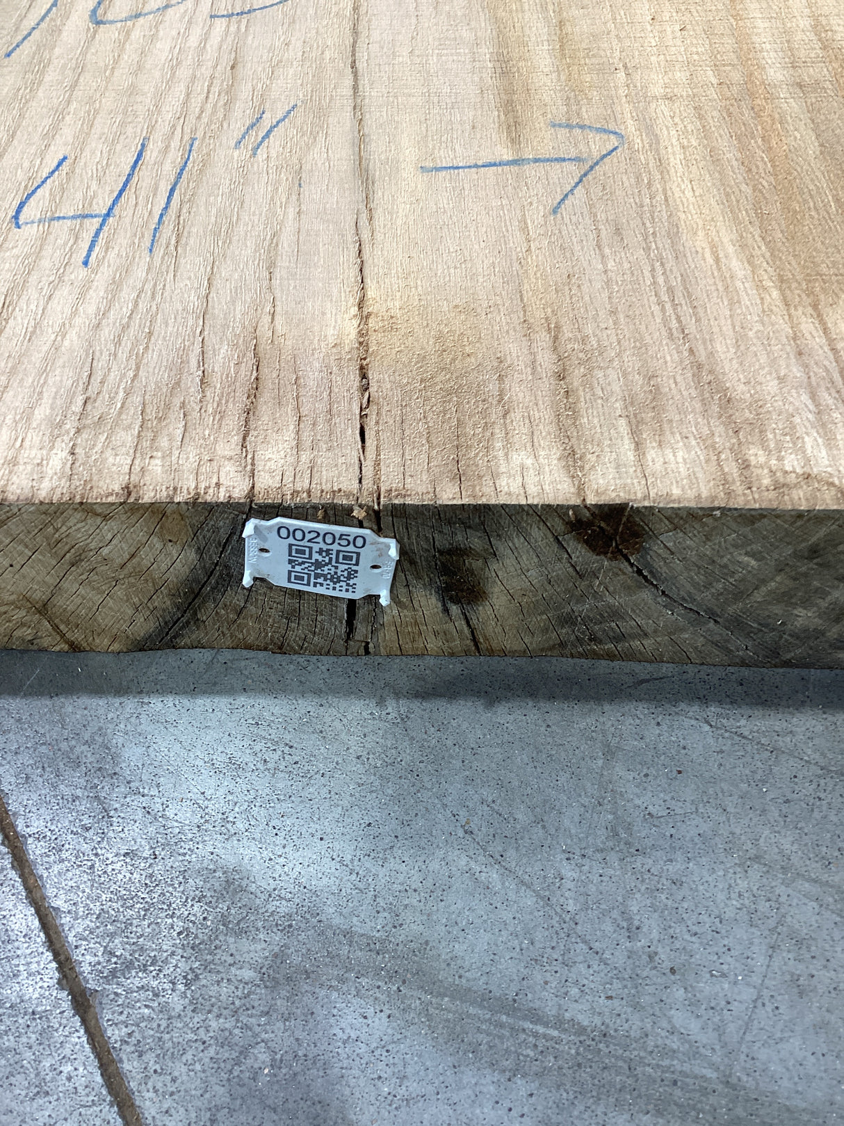 The edge of a beige-colored oak wood slab with visible sku and QR code attached.