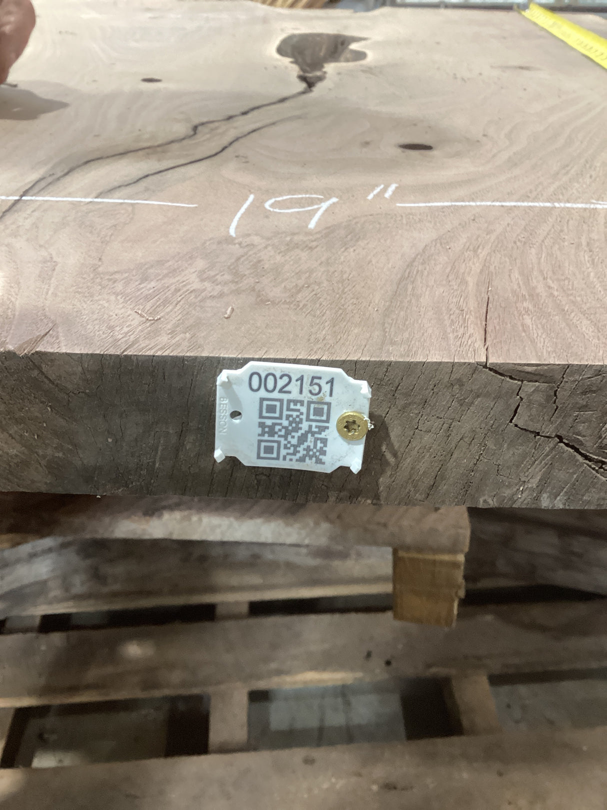 A walnut slab with a visible natural center void, marked with a measurement of 19 inches and a QR code tag.