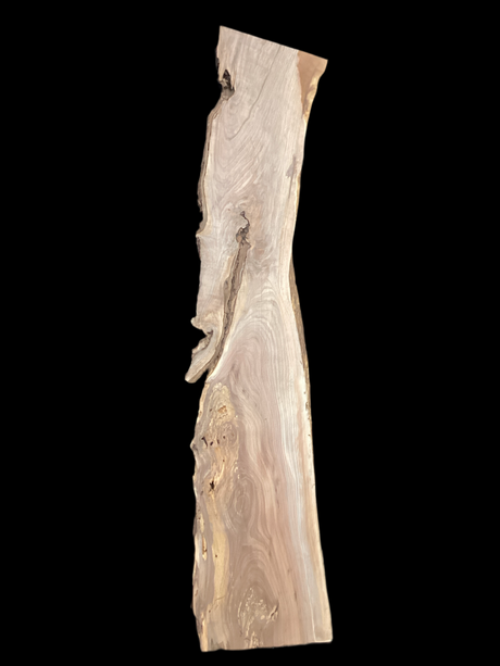 A long walnut slab with a black background. 