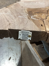 A walnut wood slab with a visible wood grain and a tag with a QR code attached to it.