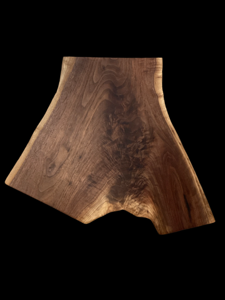 A walnut charcuterie board with a natural edge and a smooth finish.