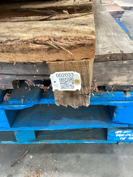 QR code attached to the Osage Orange wood table legs stacked on a wooden pallet in a warehouse setting.