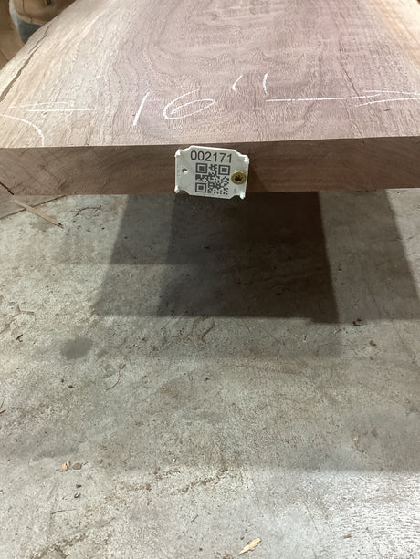 A walnut wood slab with a QR code tag attached to it, displaying potential design uses.