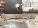 Large walnut wood slab propped on pallets being held up by a man.