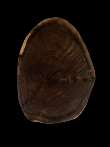 A round walnut charcuterie board with visible cracks and a darker center, surrounded by a lighter walnut border.