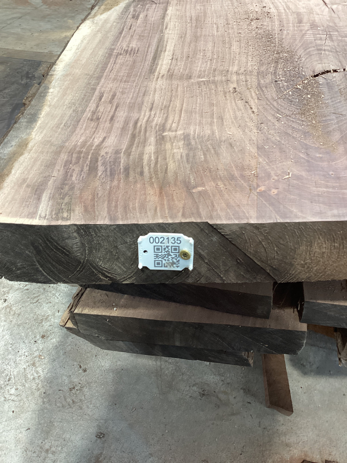 A walnut slab with a visible QR label in the bottom right corner, showcasing the wood's natural grain and color.