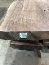 A walnut slab with a visible QR label in the bottom right corner, showcasing the wood's natural grain and color.
