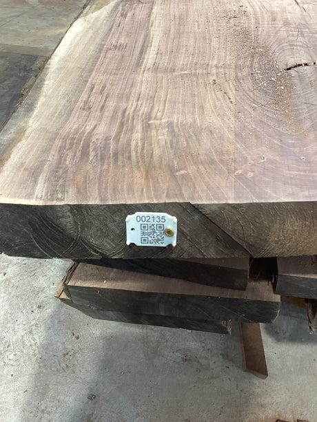 A walnut slab with a visible QR label in the bottom right corner, showcasing the wood's natural grain and color.