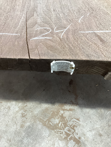 A walnut wood slab with visible growth rings and a QR label attached to it.