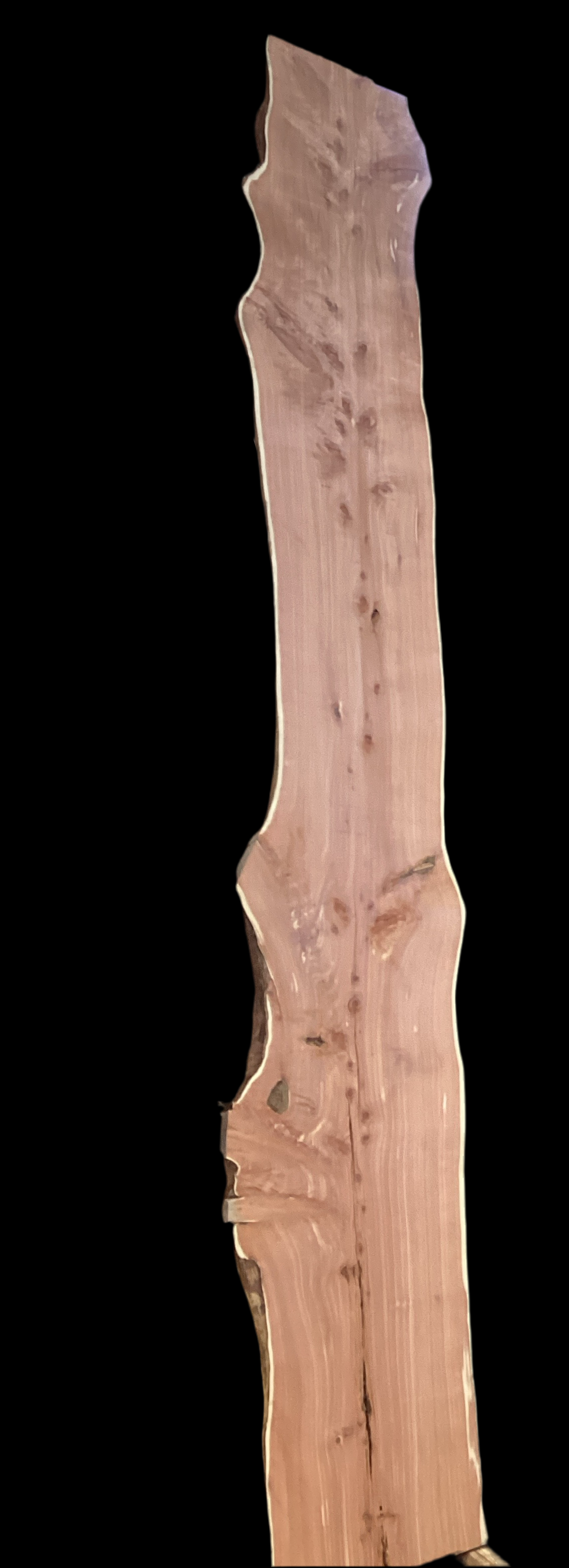 A close-up of a piece of aromatic eastern red cedar wood with visible knots and color variations.
