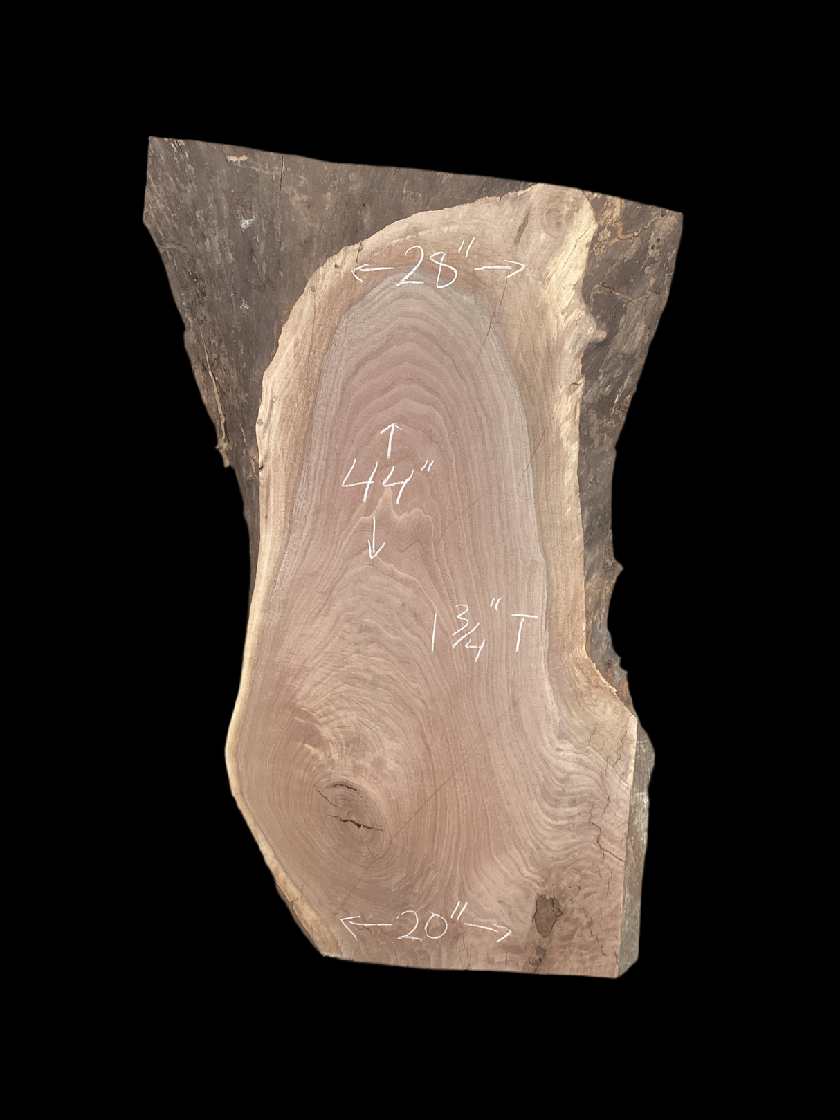 A irregular shaped walnut slab with a black background. 