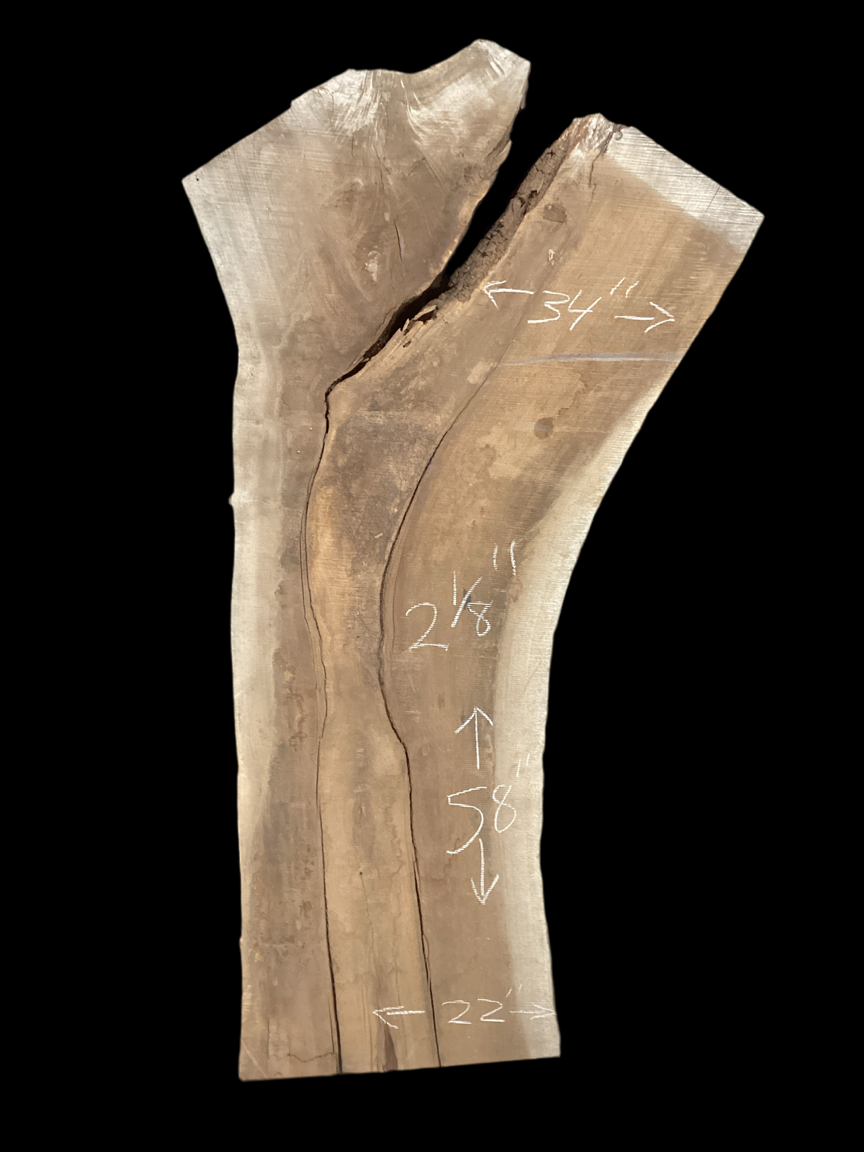 A long walnut slab with a black background. 