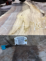 A walnut slab with visible natural color contrast and growth rings, marked with a tag containing a QR code.