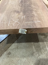 A walnut wood slab with visible knots and natural edge, with a QR label attached.