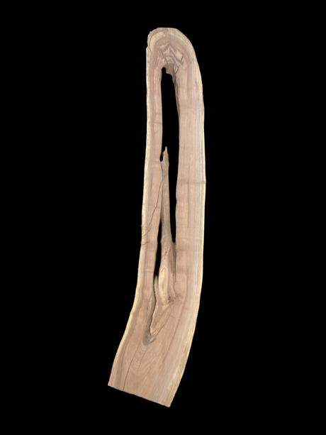 A long walnut slab, with a long hole running down the middle, and on a black background. 
