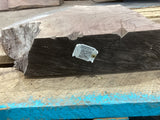 A walnut slab with a visible label on it, placed on a wooden surface with blue and green markings.