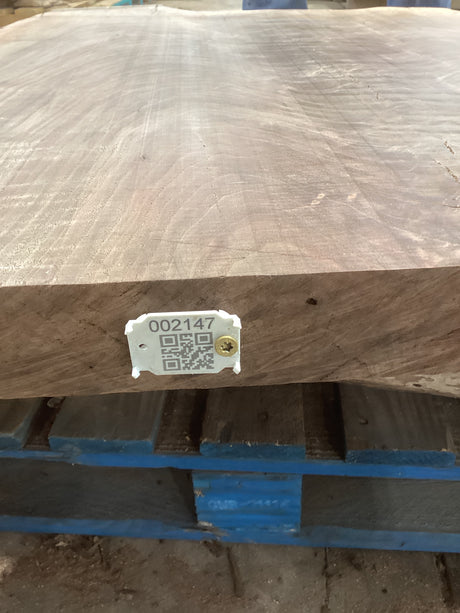A walnut slab with a distinctive figure, featuring a QR code on a white label attached to the edge.